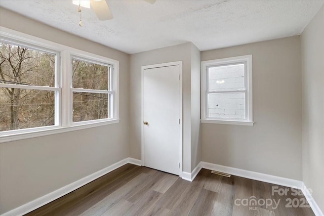 unfurnished bedroom with a textured ceiling, a ceiling fan, baseboards, and wood finished floors