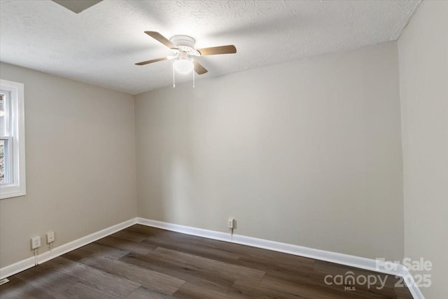 spare room featuring baseboards, dark wood-type flooring, a ceiling fan, and a textured ceiling