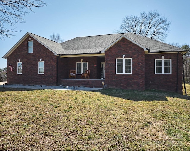 ranch-style home featuring brick siding, roof with shingles, and a front lawn