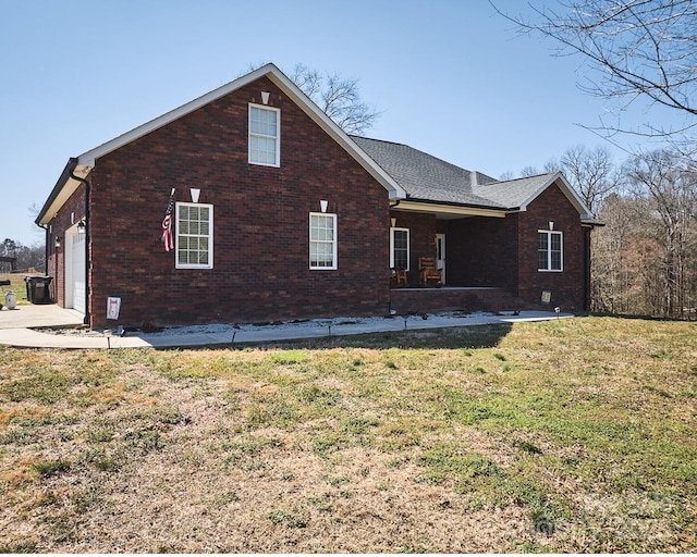 view of side of home featuring an attached garage, a lawn, and brick siding