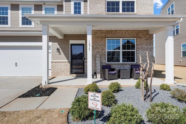 view of exterior entry featuring brick siding, covered porch, an attached garage, and driveway