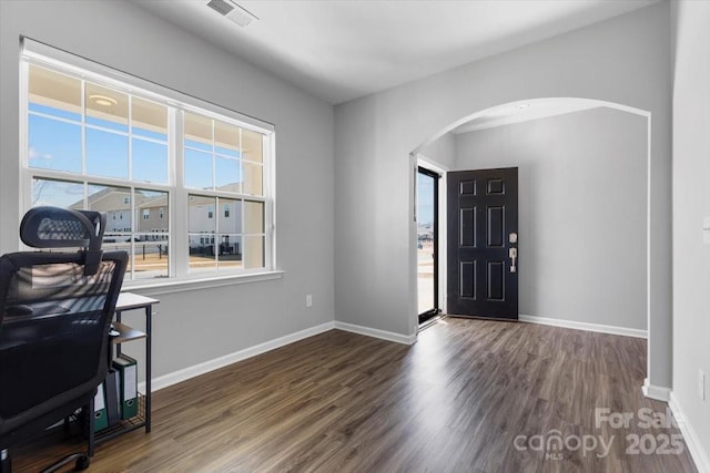 foyer featuring arched walkways, visible vents, baseboards, and wood finished floors