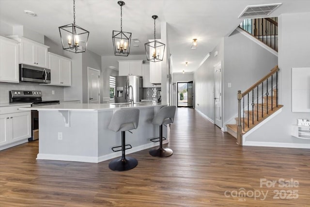 kitchen with white cabinets, tasteful backsplash, dark wood-style flooring, and stainless steel appliances