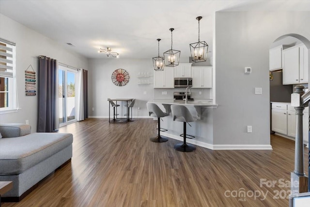 living room featuring arched walkways, visible vents, dark wood-type flooring, and baseboards