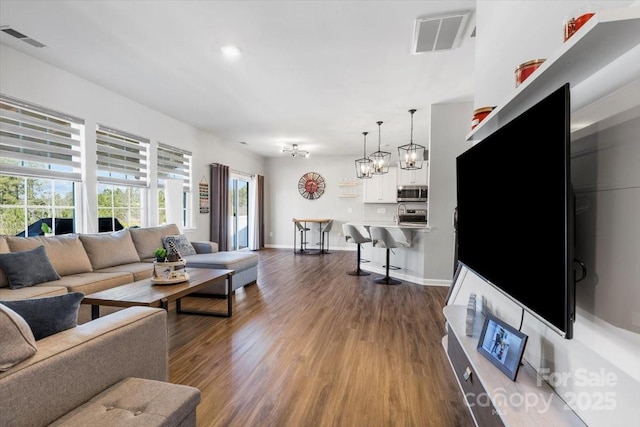 living room featuring visible vents, dark wood-type flooring, and baseboards