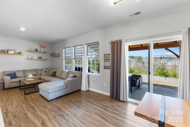 unfurnished living room with wood finished floors, visible vents, and baseboards