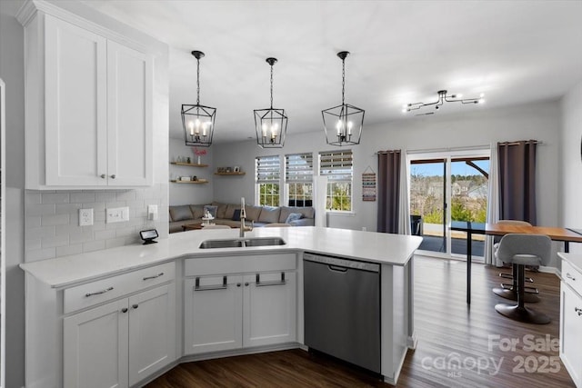 kitchen with open floor plan, light countertops, a peninsula, stainless steel dishwasher, and a sink