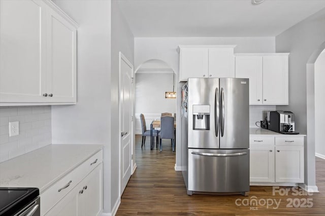 kitchen featuring white cabinets, stainless steel fridge with ice dispenser, arched walkways, and dark wood-style flooring