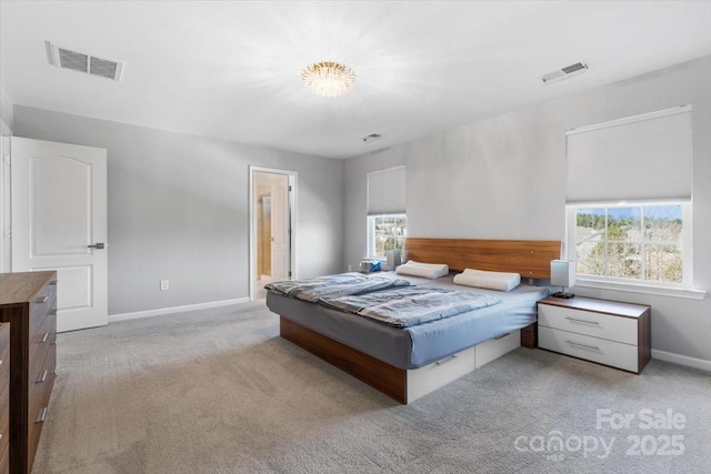 carpeted bedroom with a chandelier, visible vents, connected bathroom, and baseboards