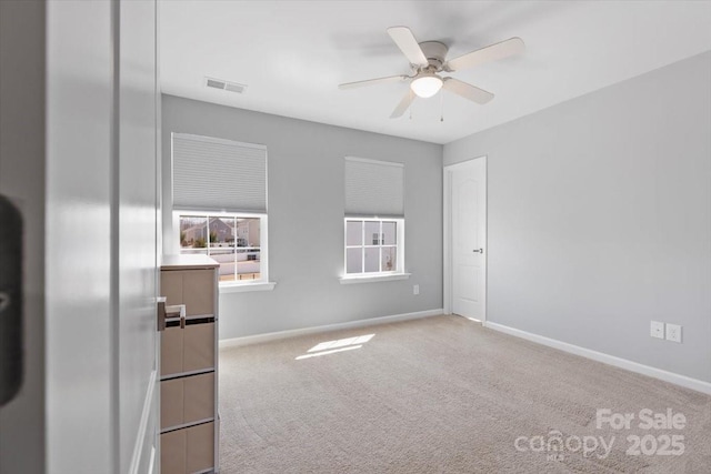 spare room featuring carpet flooring, ceiling fan, baseboards, and visible vents