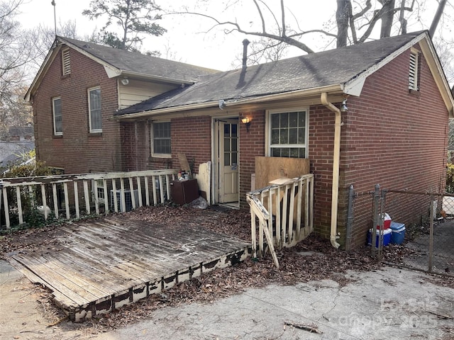 rear view of house with a deck, fence, and brick siding