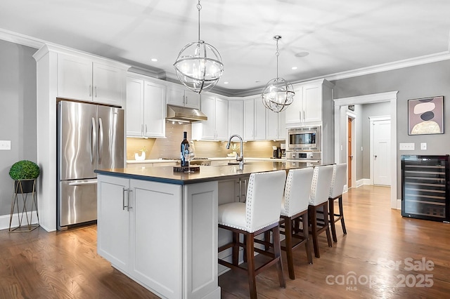 kitchen featuring under cabinet range hood, wine cooler, appliances with stainless steel finishes, and dark wood-style floors