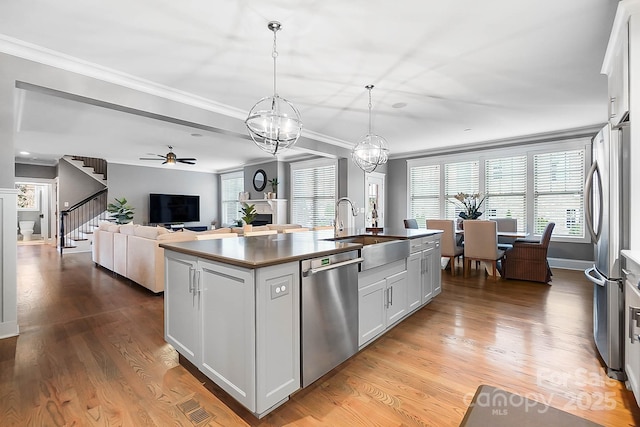 kitchen featuring a sink, ornamental molding, an island with sink, and stainless steel appliances