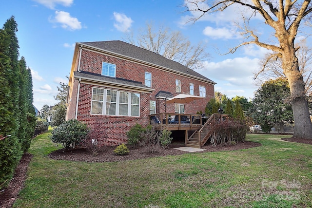 rear view of house featuring a yard, a shingled roof, a wooden deck, brick siding, and stairs