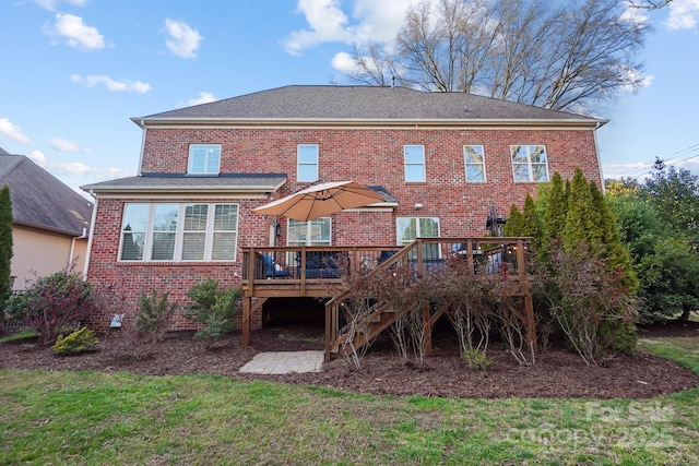 rear view of house featuring stairway, a yard, brick siding, and a wooden deck