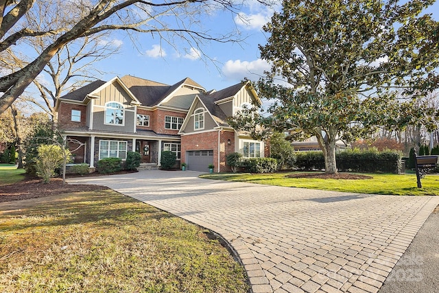 view of front of property with an attached garage, brick siding, a front lawn, decorative driveway, and board and batten siding