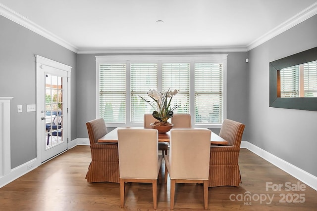 dining space featuring baseboards, wood finished floors, and ornamental molding