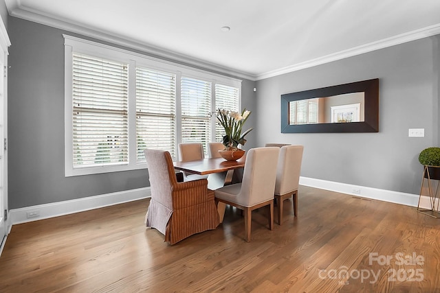 dining area with a wealth of natural light, crown molding, baseboards, and wood finished floors