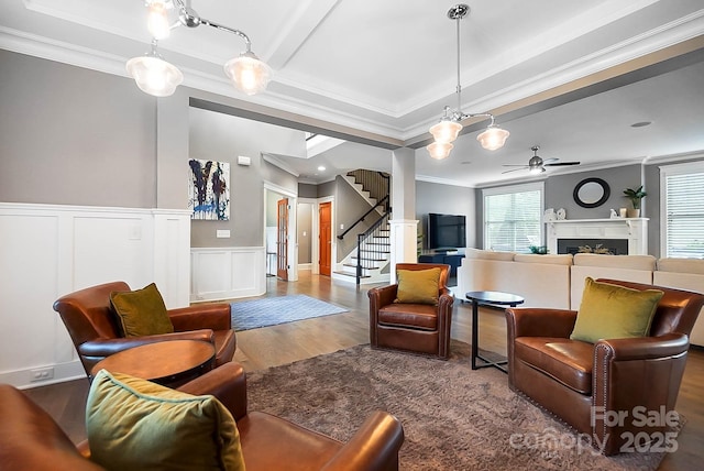 living room with crown molding, stairway, a fireplace, wood finished floors, and a ceiling fan