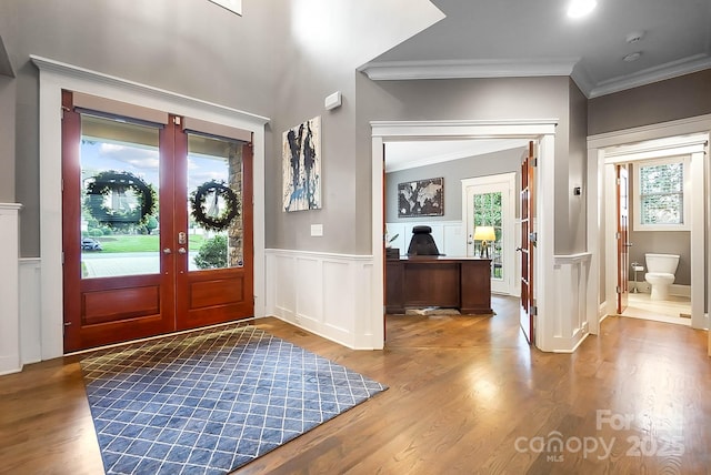 entryway featuring french doors, a wainscoted wall, wood finished floors, and crown molding