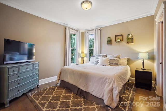 bedroom featuring dark wood-style floors, baseboards, and ornamental molding