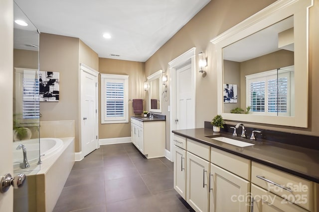 full bath with a sink, a garden tub, two vanities, and tile patterned floors