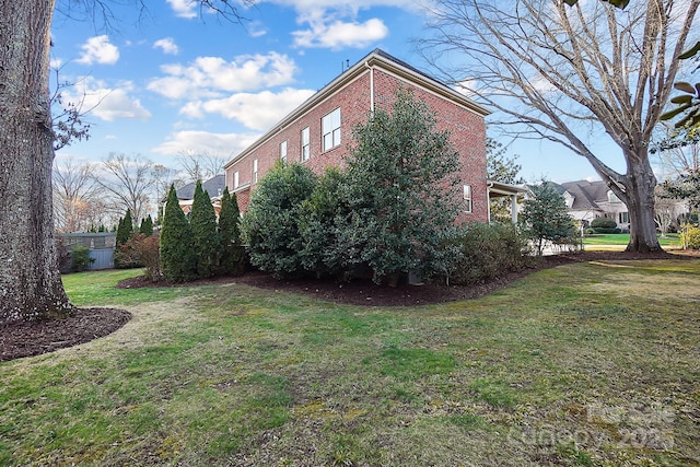 view of home's exterior with a lawn and brick siding