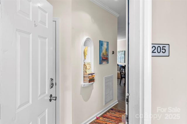 corridor with visible vents, baseboards, wood finished floors, and crown molding