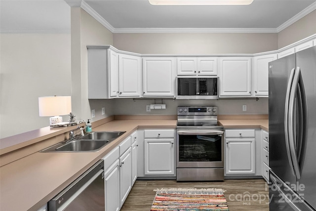 kitchen with dark wood-style flooring, stainless steel appliances, crown molding, and a sink