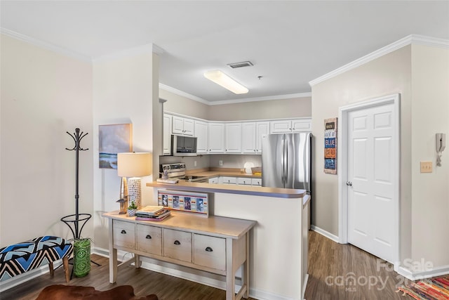 kitchen with wood finished floors, visible vents, ornamental molding, stainless steel appliances, and white cabinetry