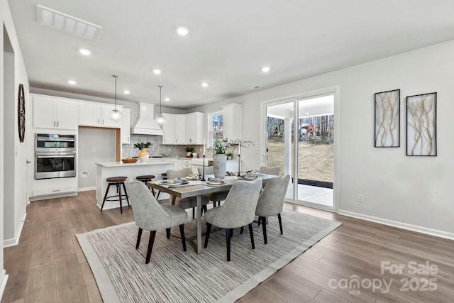 dining room featuring recessed lighting, baseboards, visible vents, and light wood finished floors