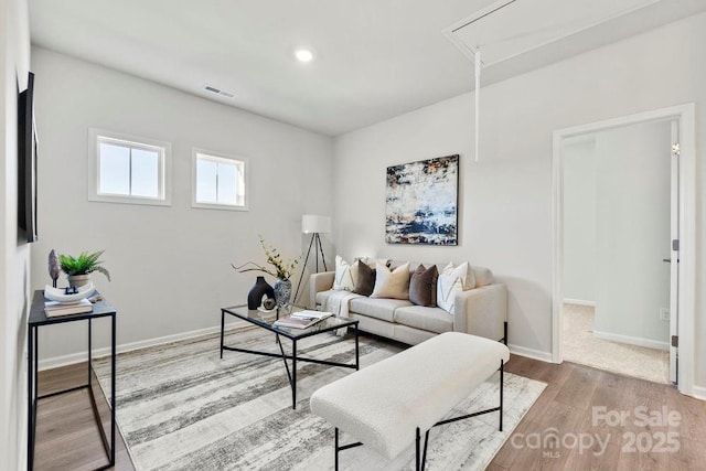 living room with visible vents, attic access, baseboards, and wood finished floors