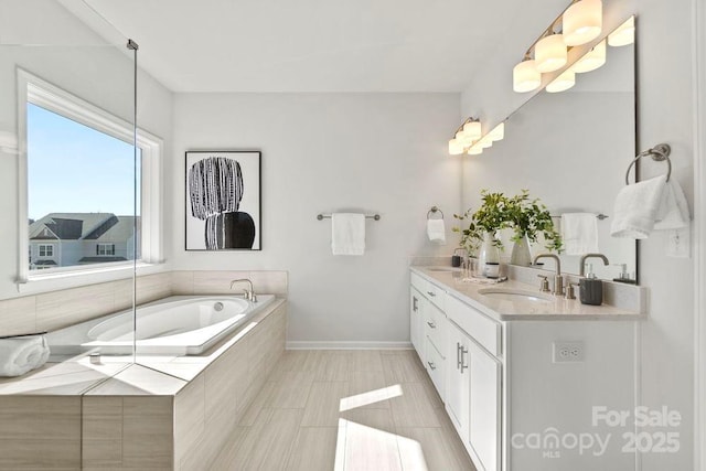 full bath featuring a sink, baseboards, a garden tub, and double vanity