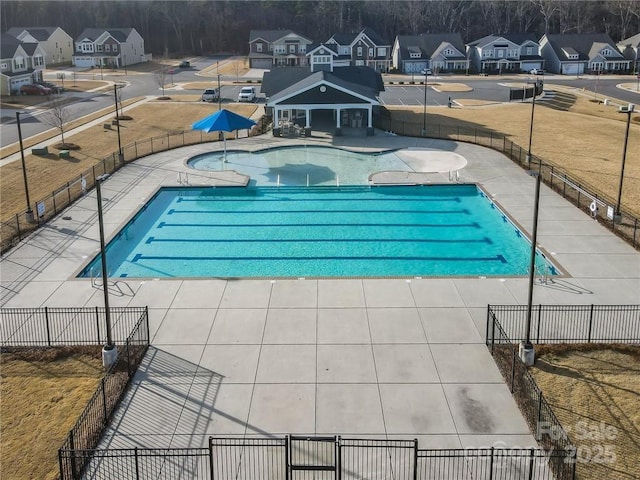 pool with a yard, a residential view, a patio, and fence