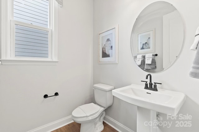 bathroom with a sink, toilet, baseboards, and wood finished floors