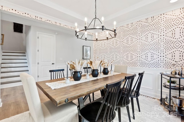 dining area with stairs, a decorative wall, a wainscoted wall, and light wood finished floors