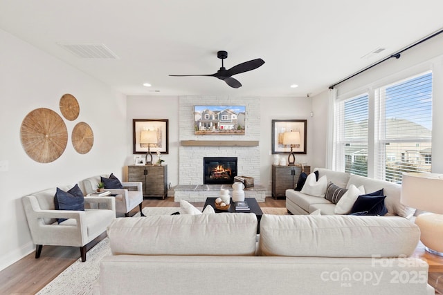 living room featuring visible vents, wood finished floors, recessed lighting, a stone fireplace, and baseboards