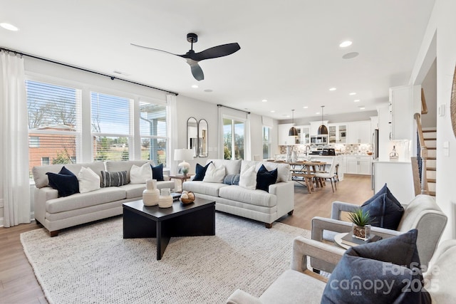 living room featuring recessed lighting, a ceiling fan, light wood-style flooring, and stairs