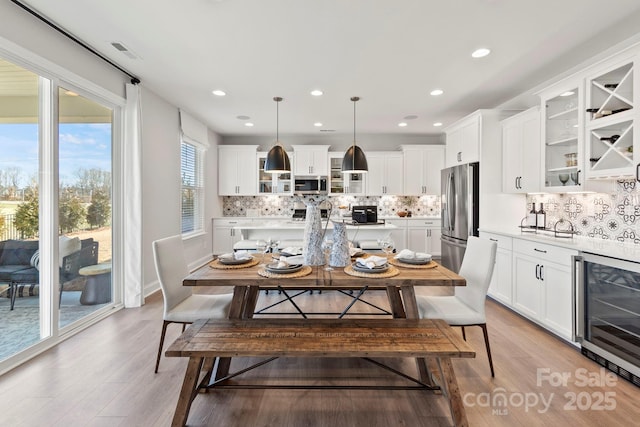 dining space featuring recessed lighting, visible vents, wine cooler, and light wood-style floors