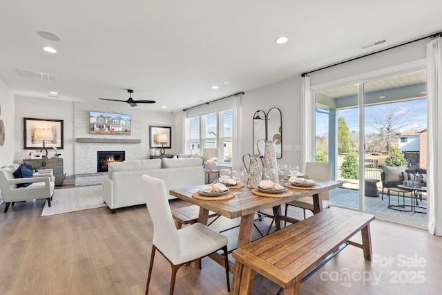 dining area featuring light wood-style flooring, recessed lighting, a fireplace, and visible vents