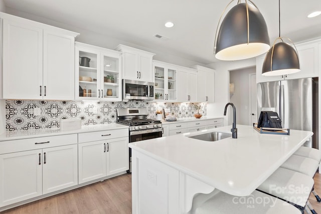 kitchen featuring a sink, appliances with stainless steel finishes, a breakfast bar, and light countertops