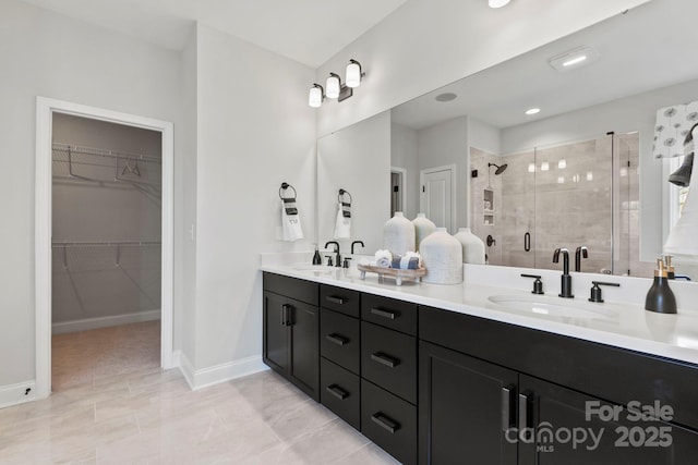 bathroom with double vanity, a spacious closet, a stall shower, and a sink