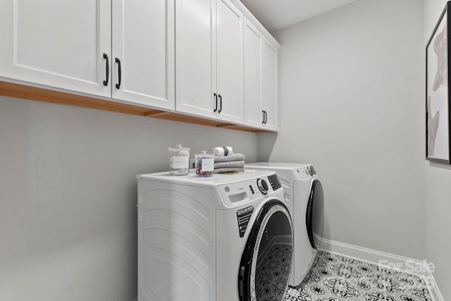 laundry area featuring light tile patterned floors, baseboards, cabinet space, and washer and clothes dryer