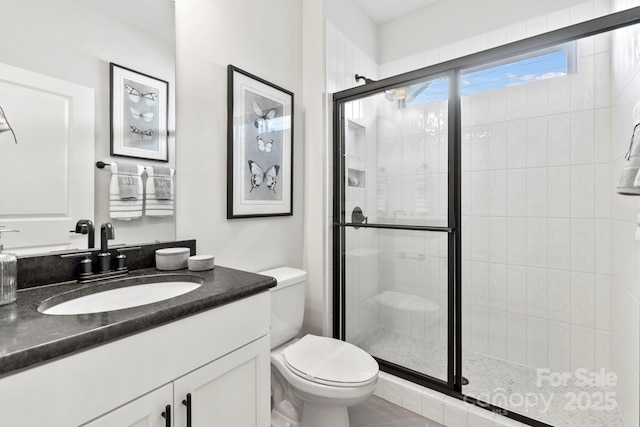 full bathroom featuring vanity, a shower stall, and toilet