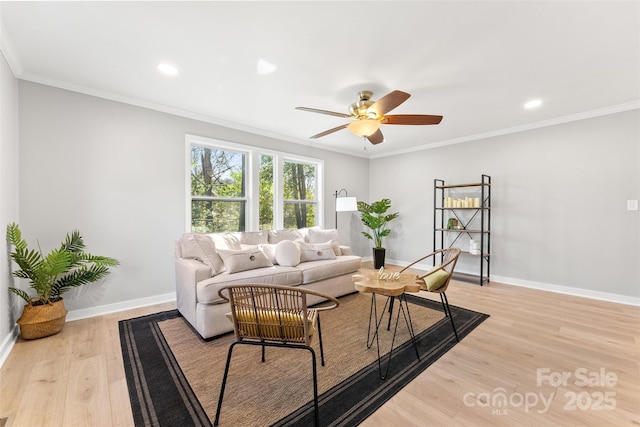 living area with baseboards, light wood-type flooring, ceiling fan, and ornamental molding