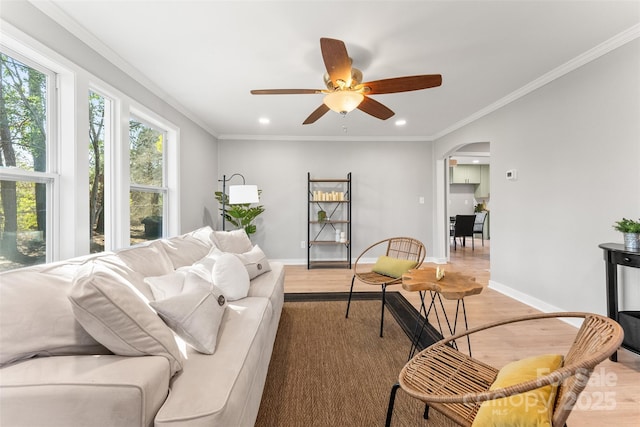 living room with baseboards, arched walkways, wood finished floors, and crown molding