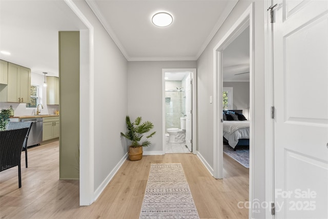 hallway with crown molding, baseboards, and light wood-type flooring