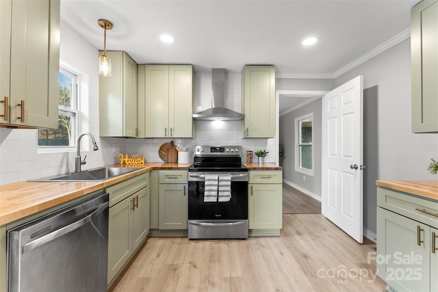 kitchen with green cabinets, wooden counters, appliances with stainless steel finishes, and wall chimney exhaust hood