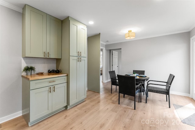 dining space with light wood-type flooring, baseboards, and ornamental molding