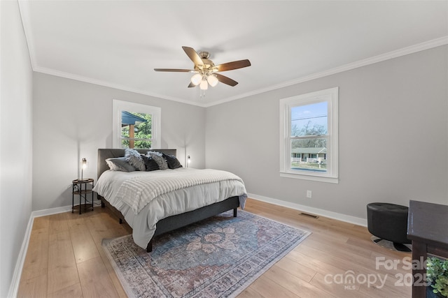 bedroom featuring crown molding, light wood-style floors, visible vents, and baseboards